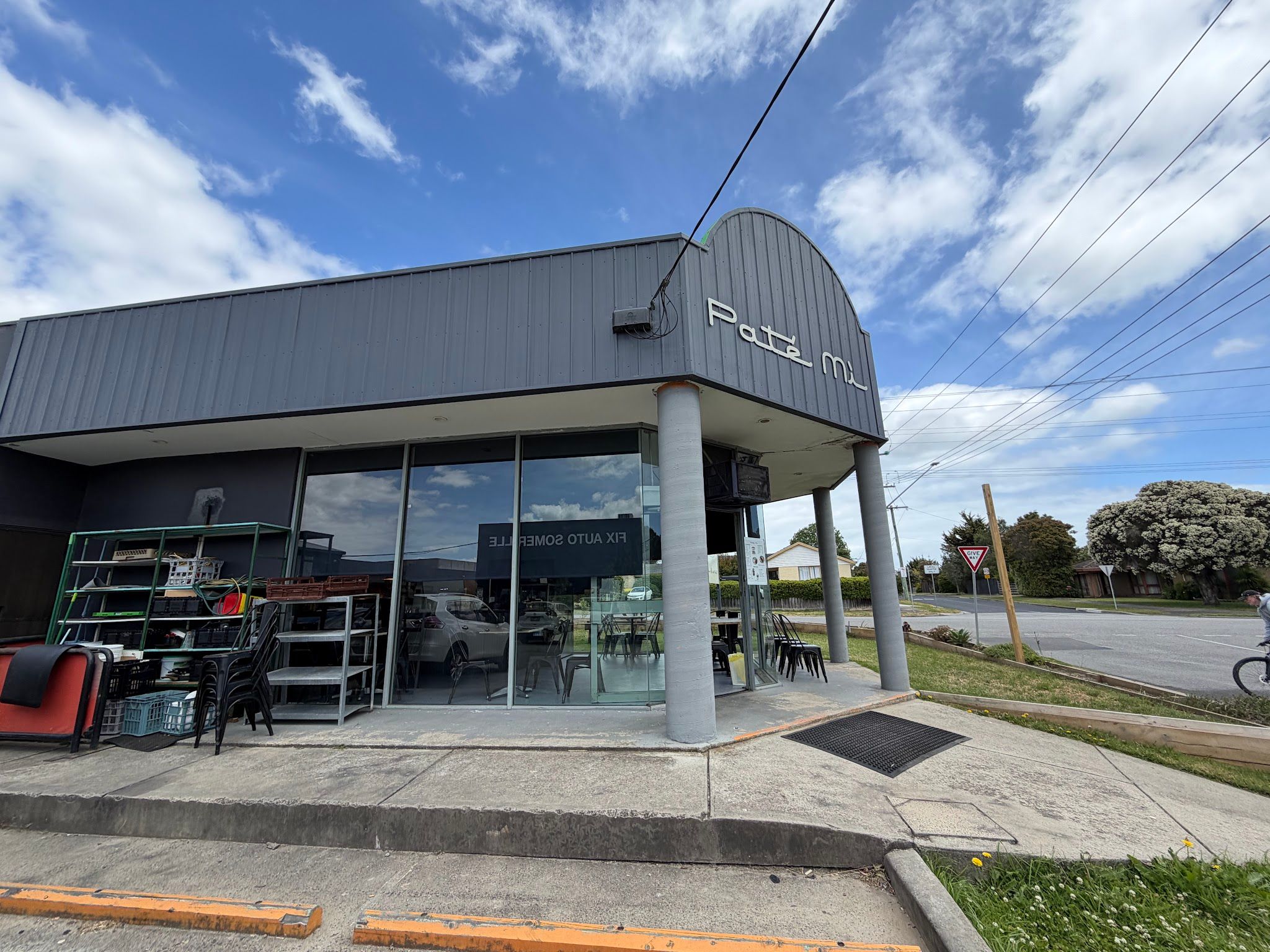 Side view of Pate Mi cafe exterior with grey cladding and large windows on an overcast day