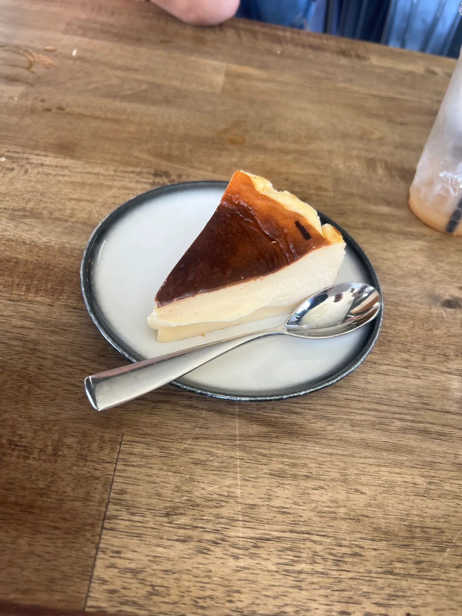 Slice of burnt Basque cheesecake with caramelised top on a white plate with a spoon