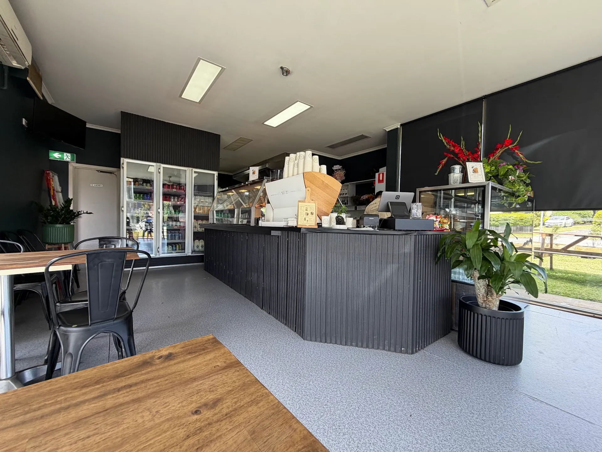 Pate Mi cafe interior with dark slatted service counter, display cabinets and potted plants